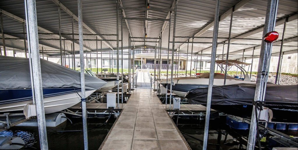 Covered dock sheltering boats, separated by a walkway, leading to a building onshore. No recognizable landmarks or historical buildings visible.